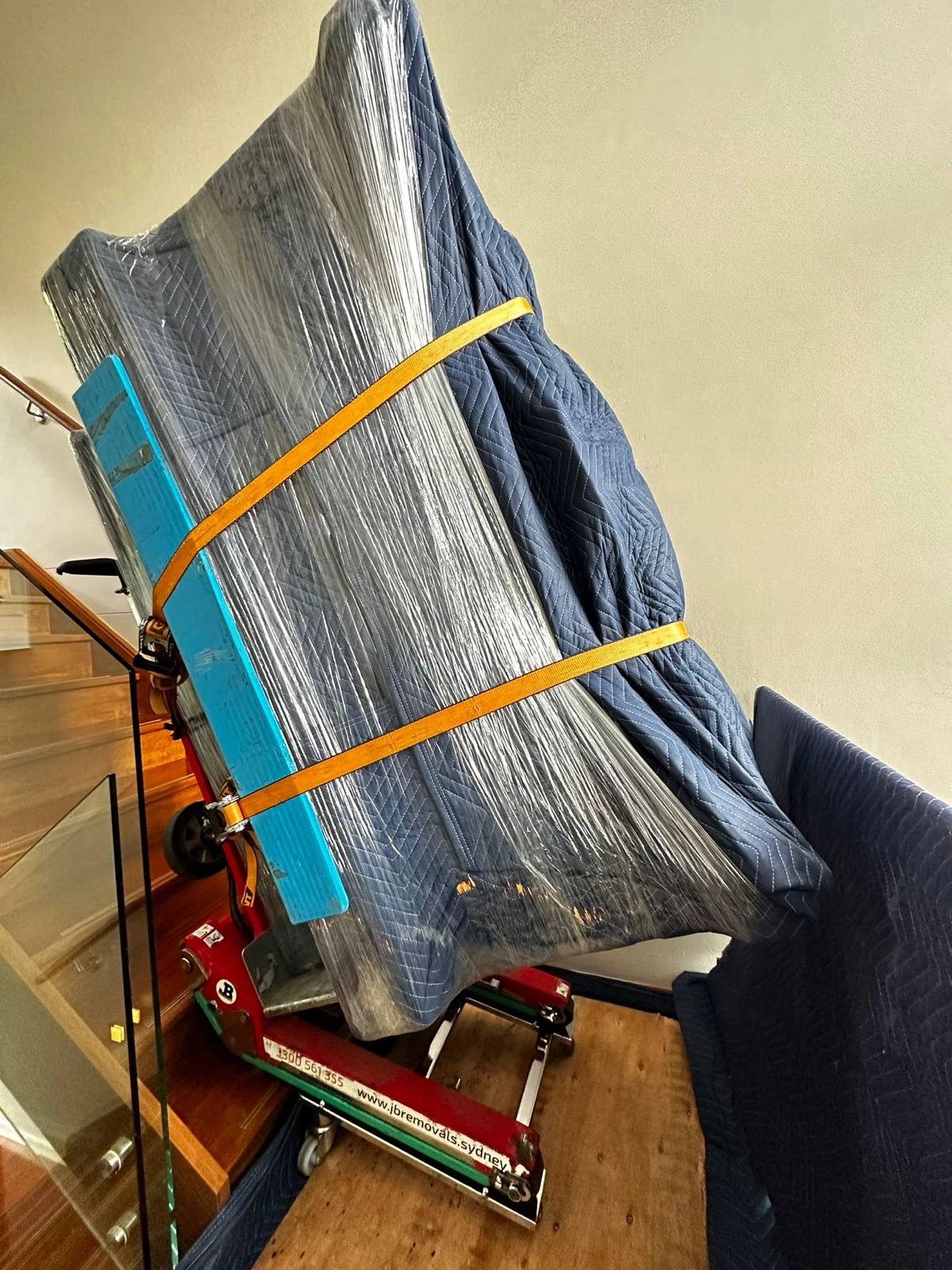Wrapped upright piano secured on specialist stair equipment inside a home