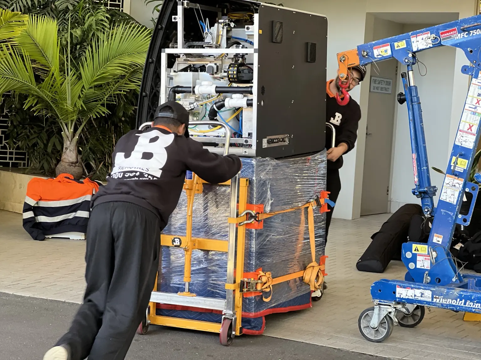 JB Removals crew using a counterweighted crane to position a German dental machine on its protected base