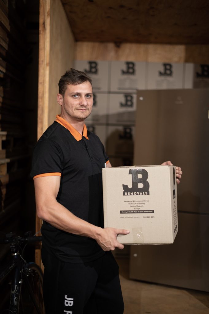 JB crew member holding a carton beside packed boxes