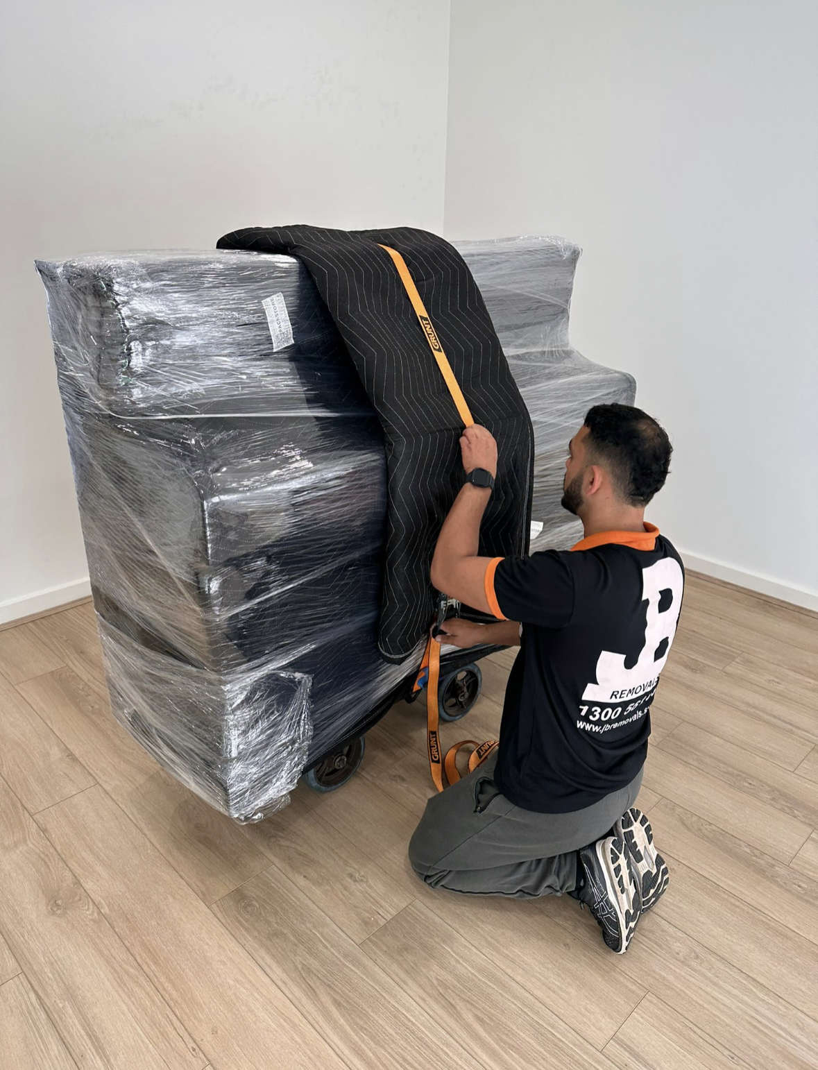 JB removalist adding protective blankets to a wrapped upright piano