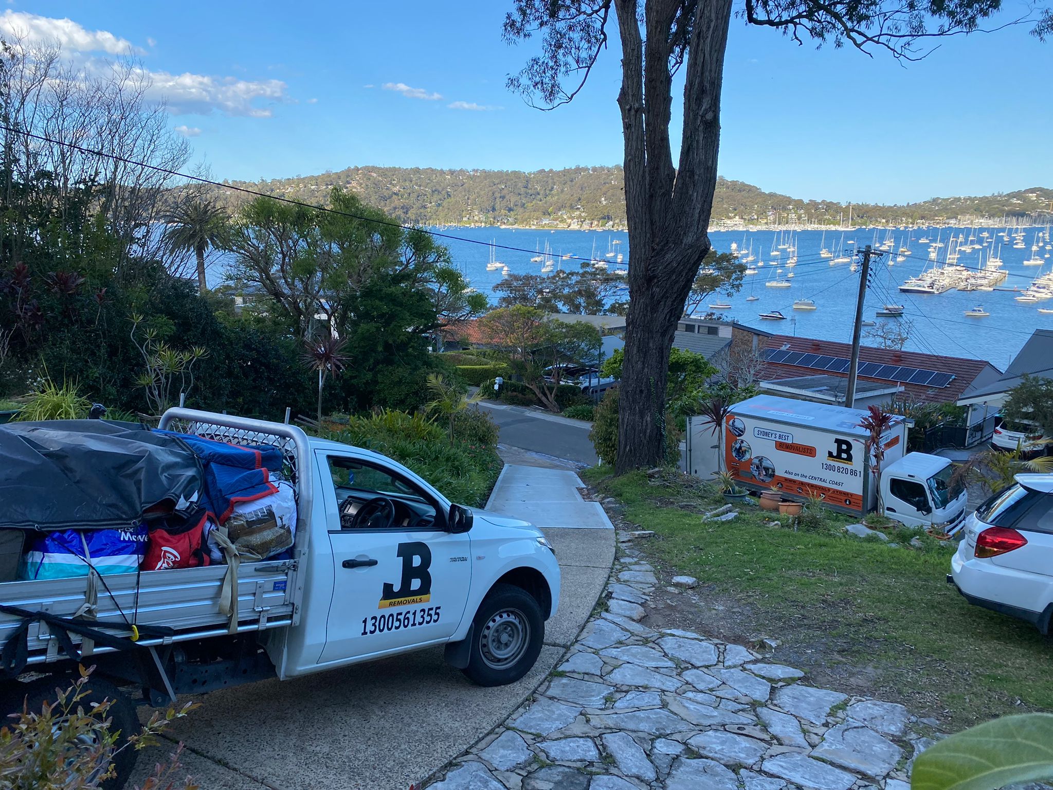JB Removals vehicles on a steep driveway overlooking the water