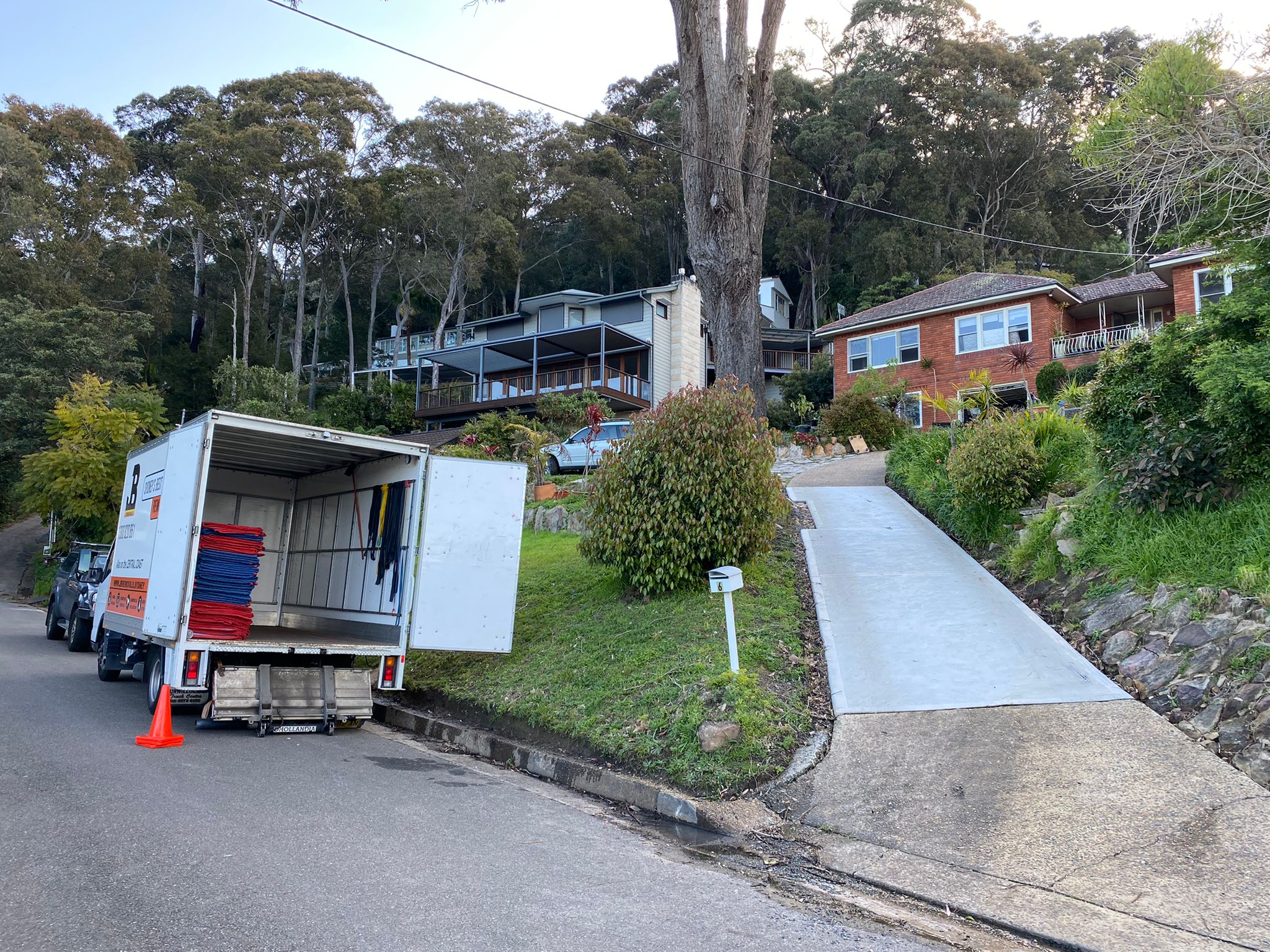 JB Removals truck parked beside a steep residential driveway