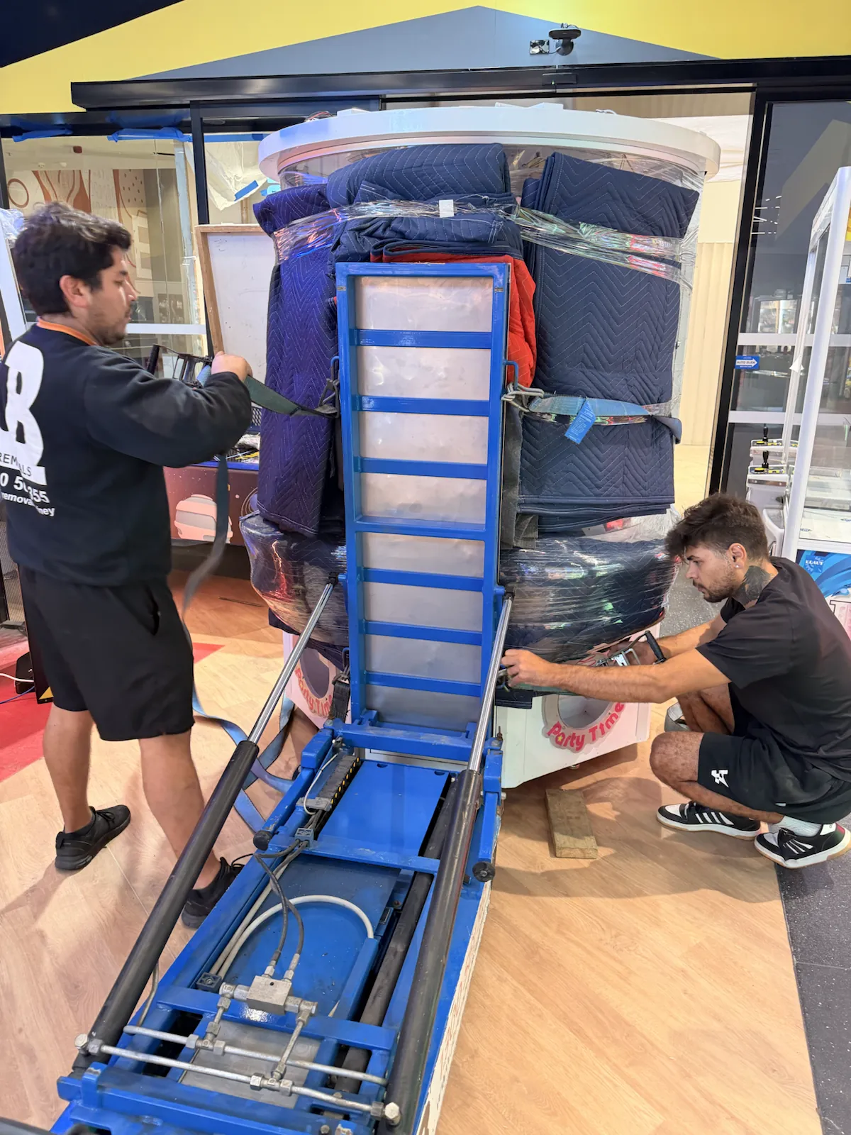 JB Removals crew securing a 700kg glass arcade machine to the Hercules system