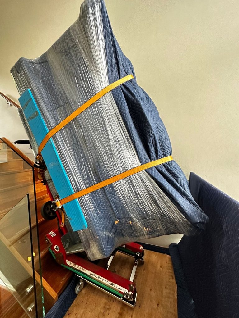 Wrapped upright piano secured on specialist stair equipment inside a home