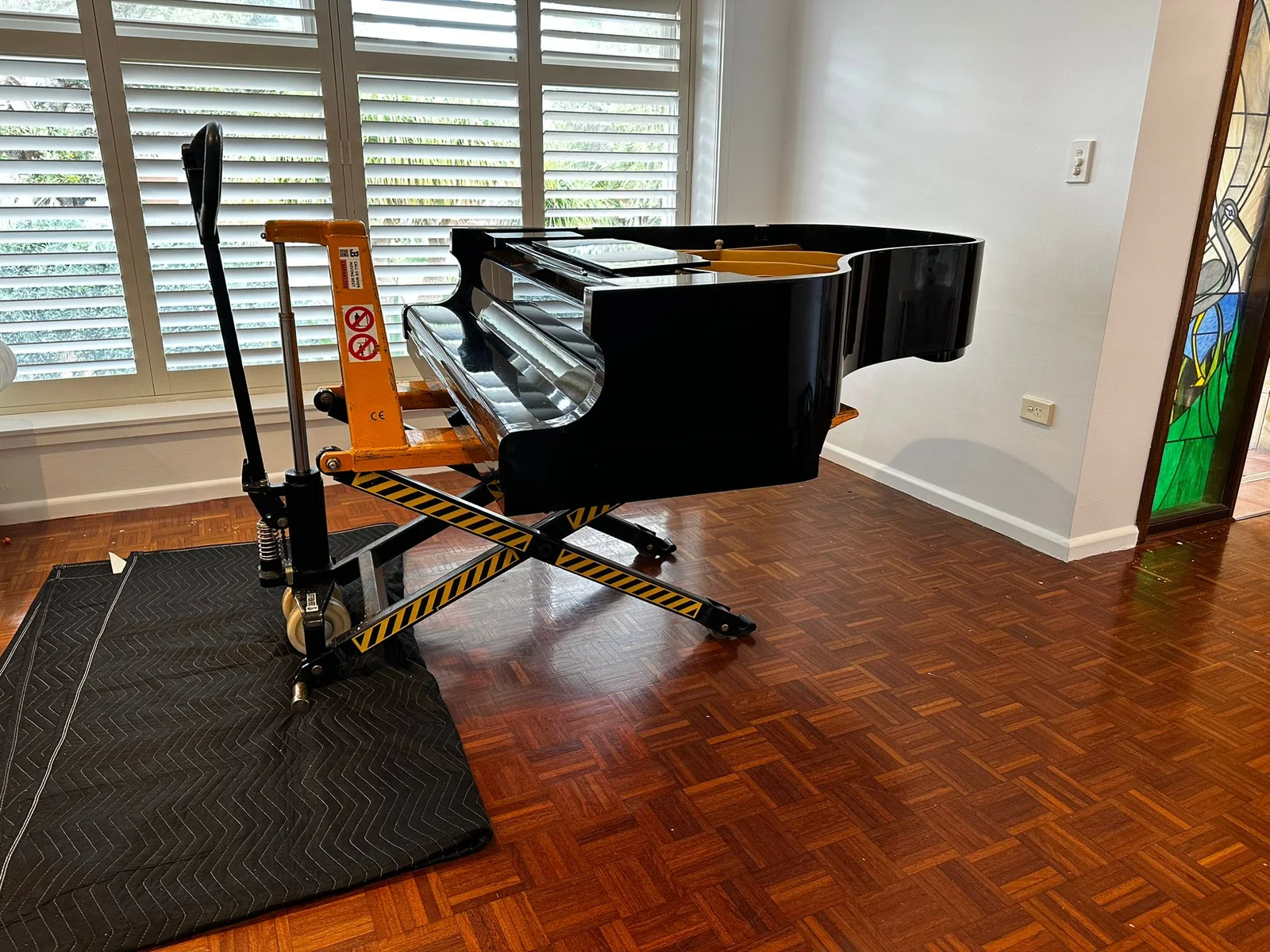Grand piano supported on specialist moving equipment with floor protection