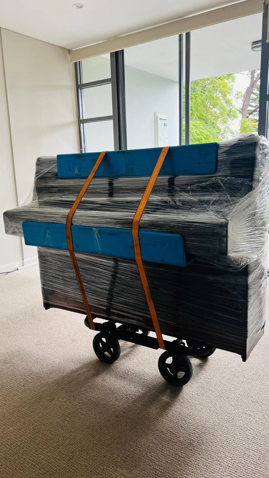 Protected upright piano secured on a moving dolly