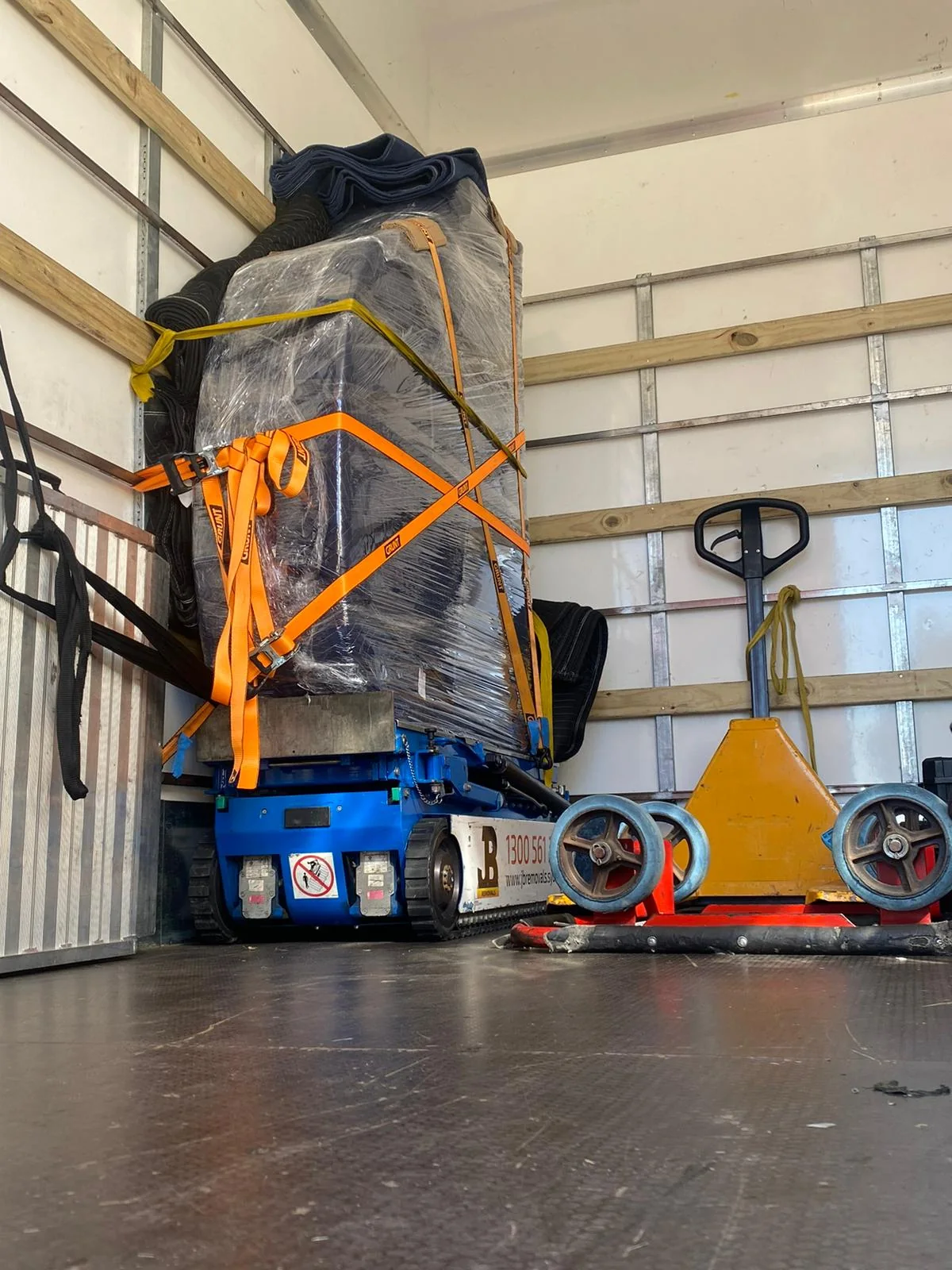 Wrapped upright piano with specialist moving equipment inside a JB truck