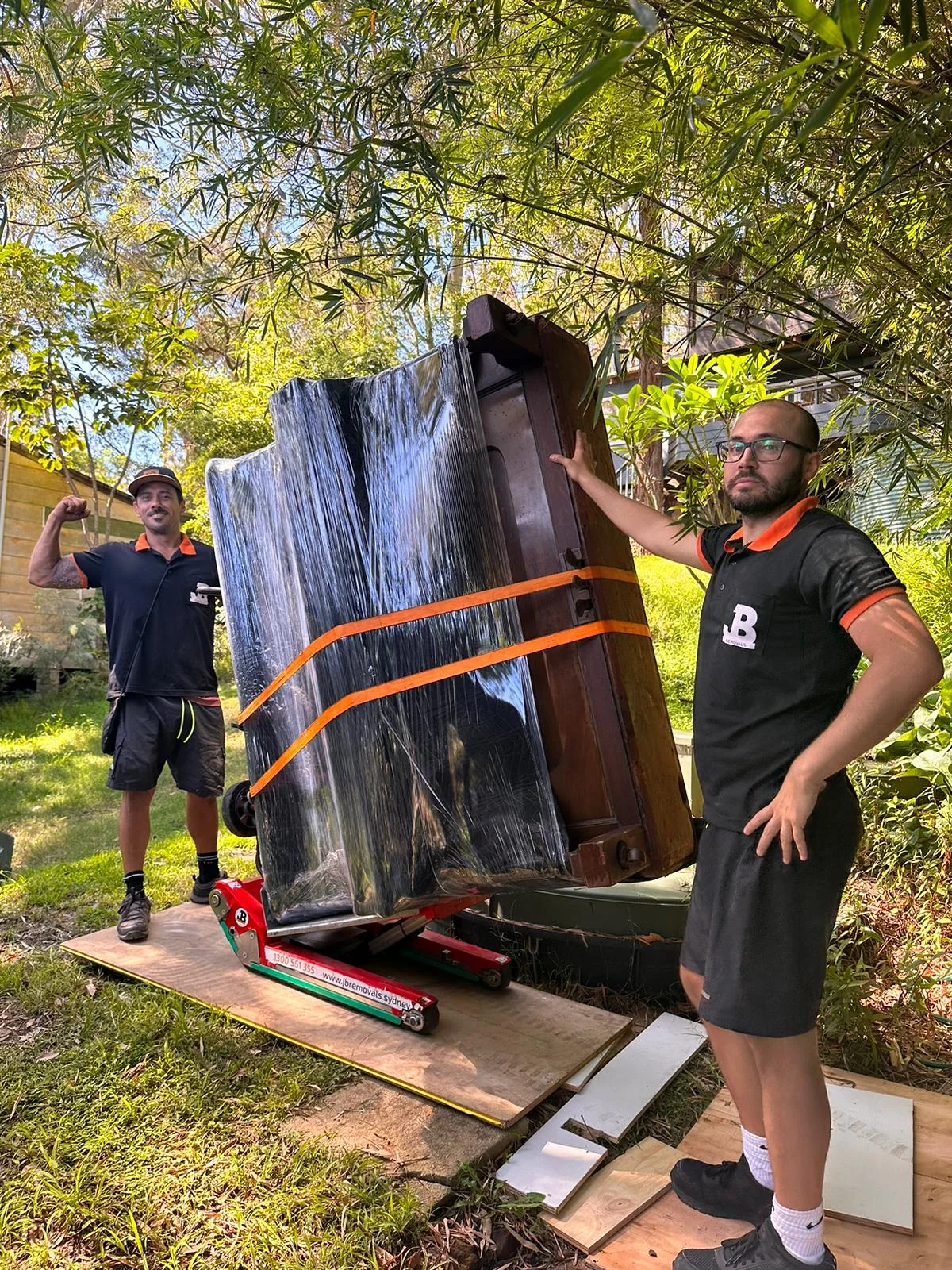 Protected upright piano on specialist moving equipment outdoors