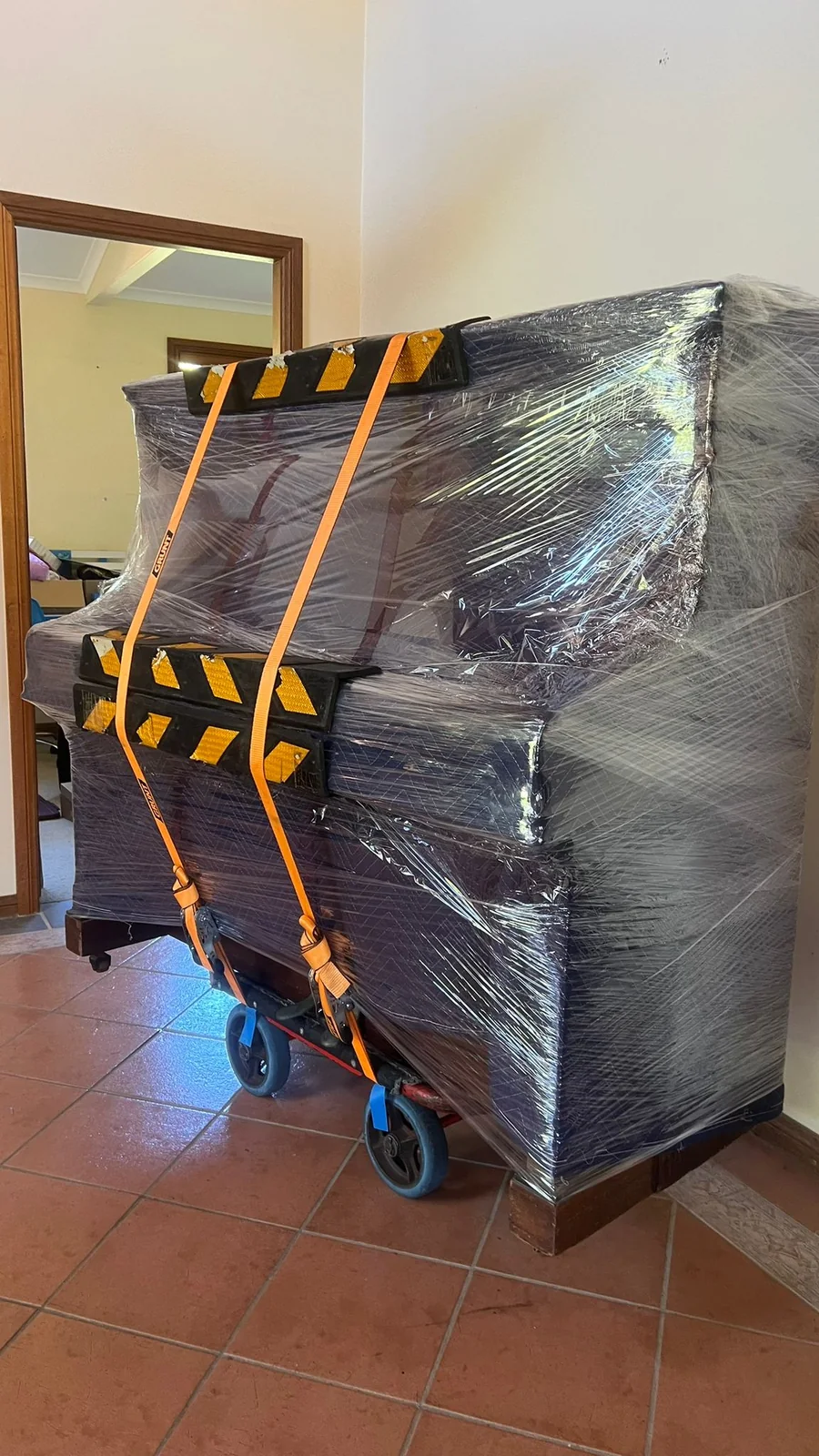 Wrapped upright piano secured on a dolly inside a Sydney property