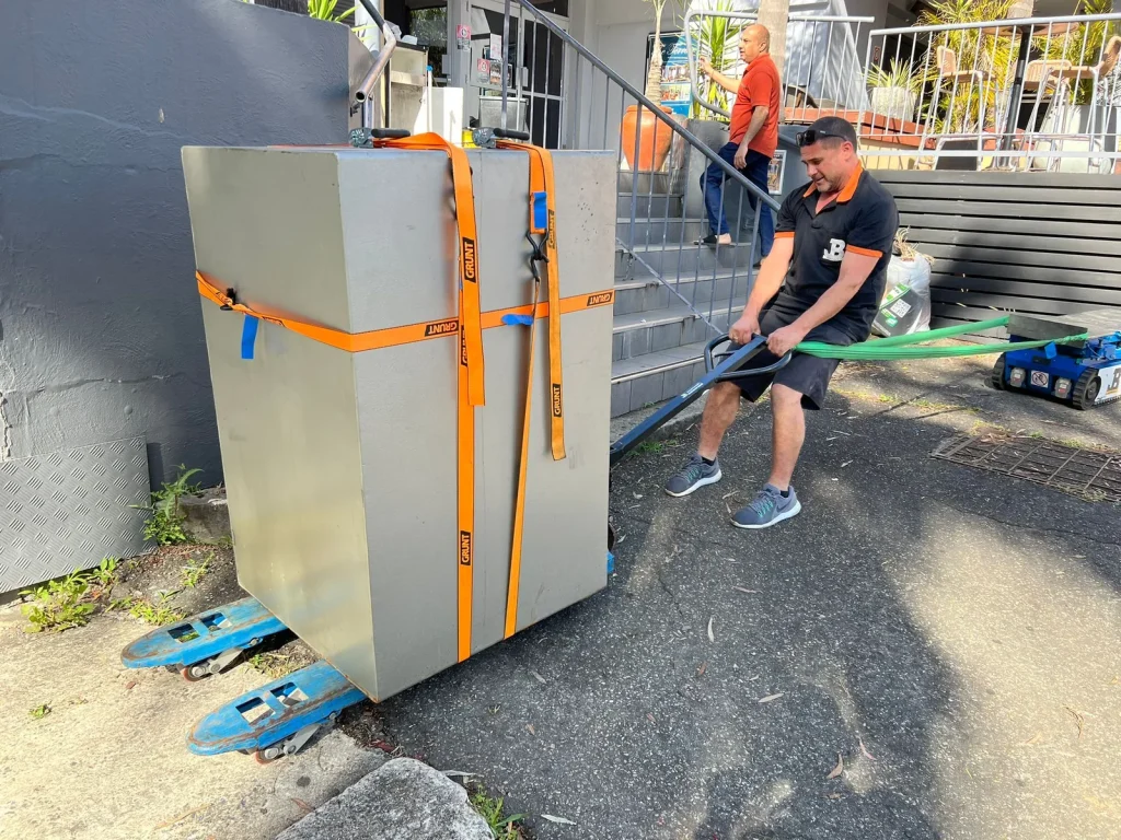 JB Removals crew guiding a secured safe through restricted outdoor access