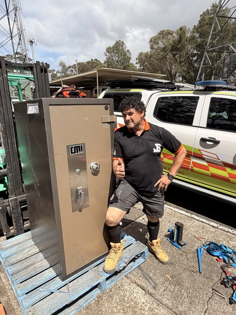 JB removalist standing beside the detached safe door outdoors after removal