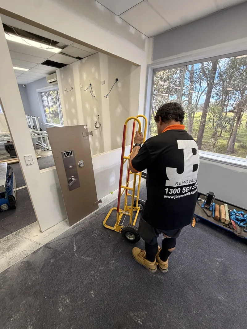 JB removalist beside the detached safe door and handling trolley inside the building
