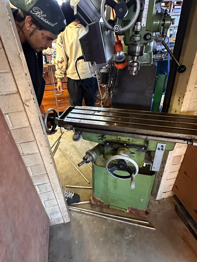 Crew member beside a milling machine at a brick workshop doorway