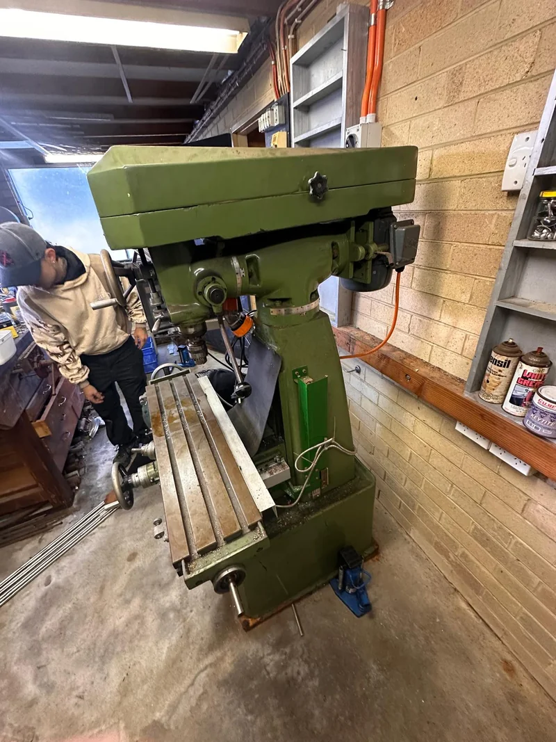 Milling machine in a workshop with a compact hydraulic jack beside its base