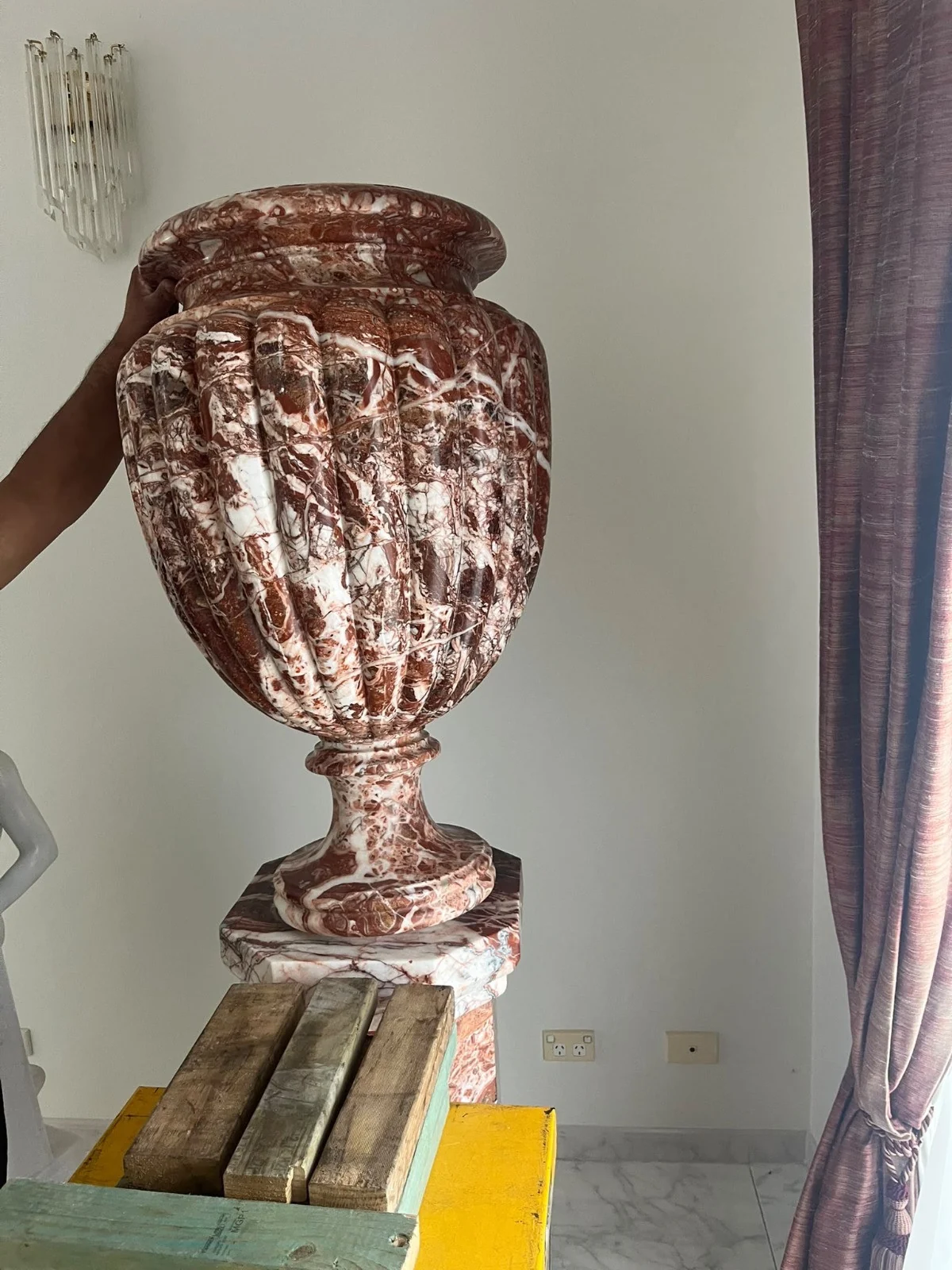 Large decorative urn on its pedestal with timber supports and a yellow platform beside it
