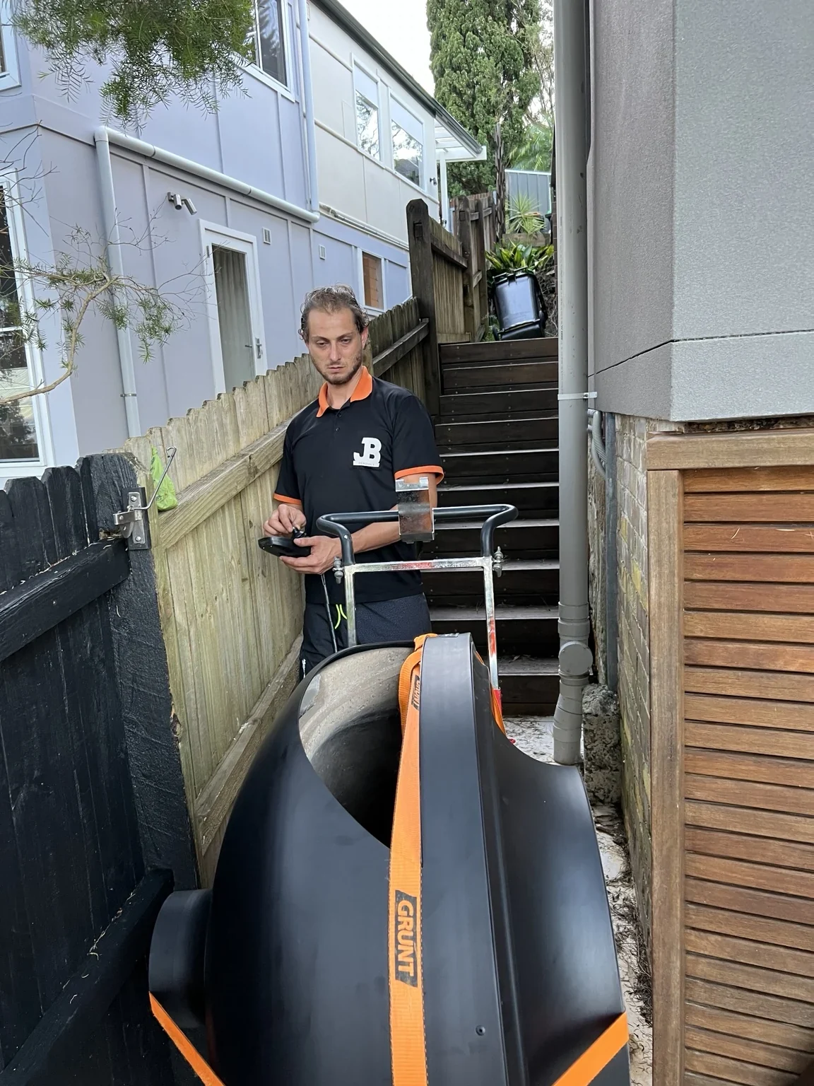 JB removalist guiding a strapped pizza oven through narrow side access