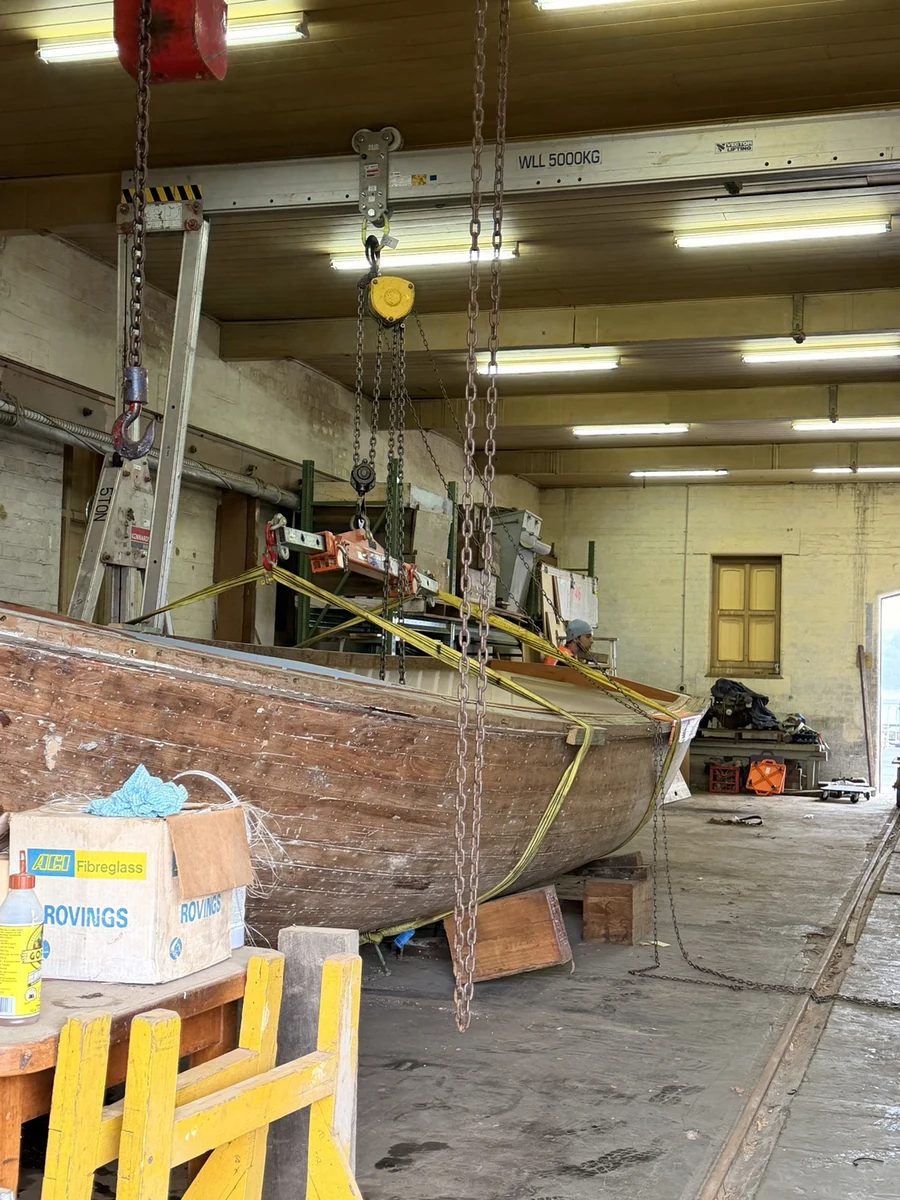Timber boat hull inside the warehouse beneath lifting equipment