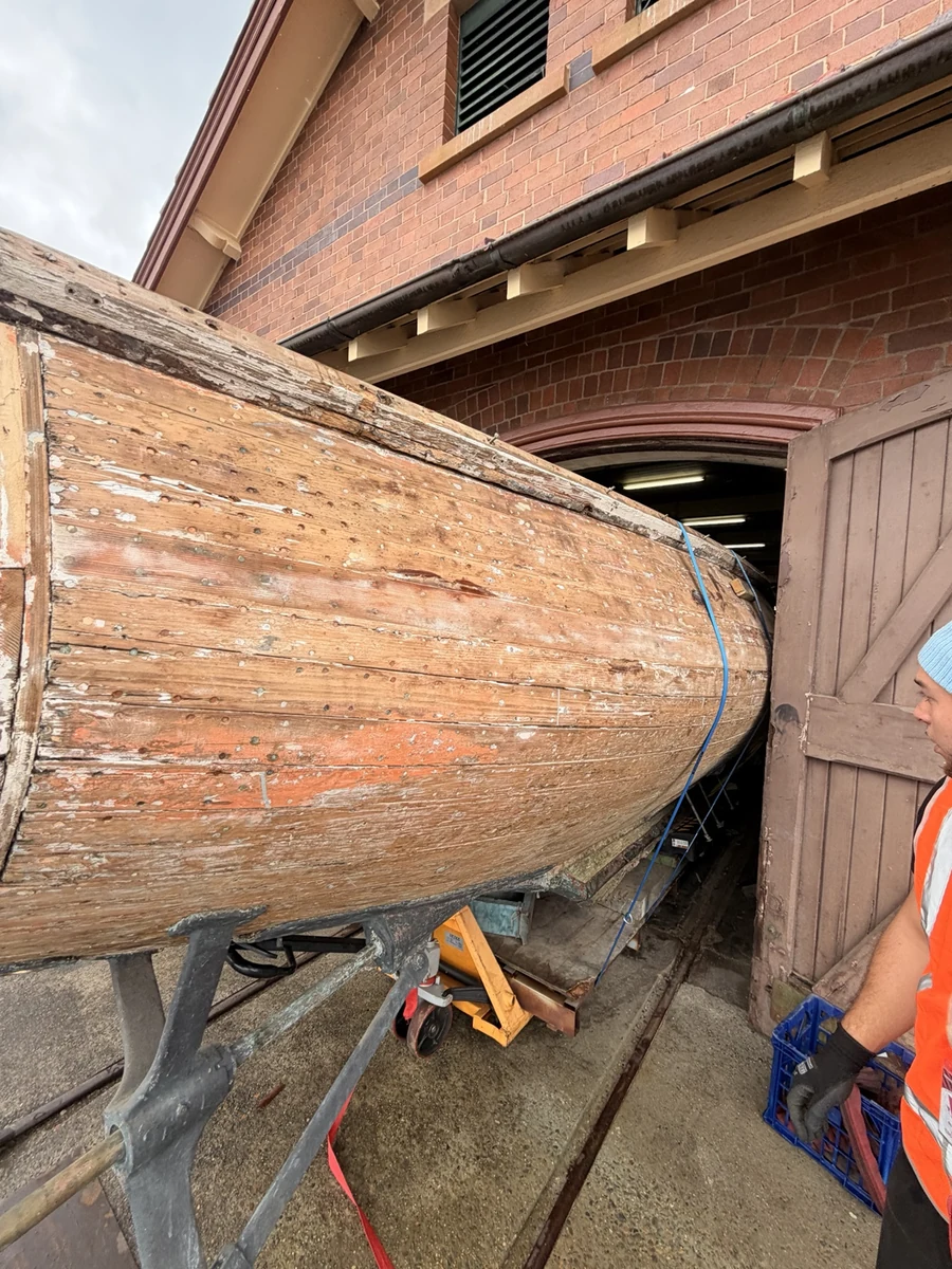 Boat hull angled through the narrow warehouse doorway