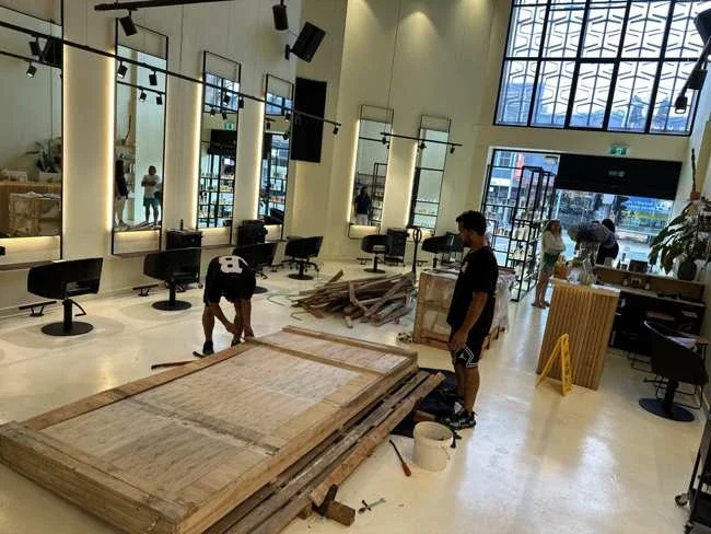 Team members beside opened timber table packaging on the salon floor
