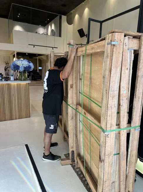 Team member beside the tall strapped timber crate inside the salon
