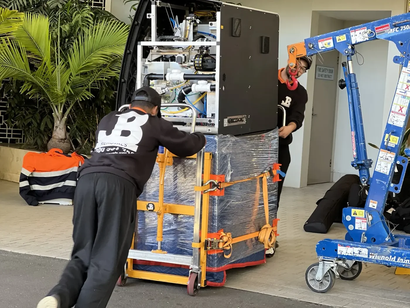 JB Removals crew using a counterweighted crane to position a German dental machine on its protected base