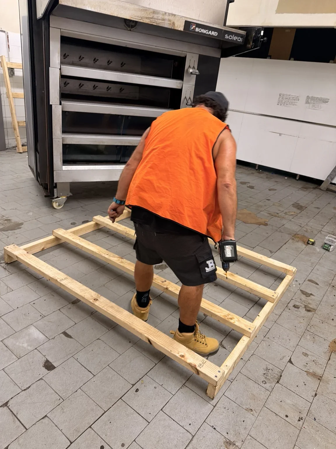 JB removalist building a timber support frame beside the commercial pizza oven