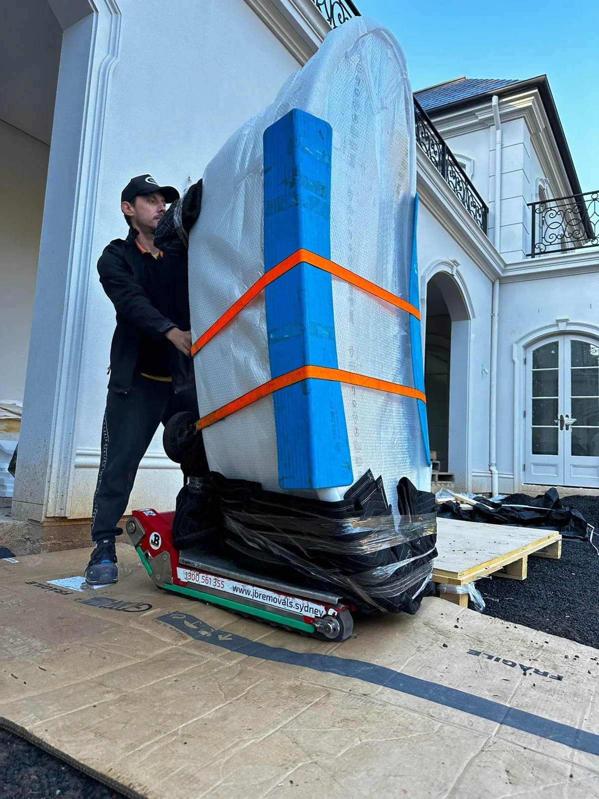 JB removalist beside an upright padded bath secured to a tracked stair-climbing unit