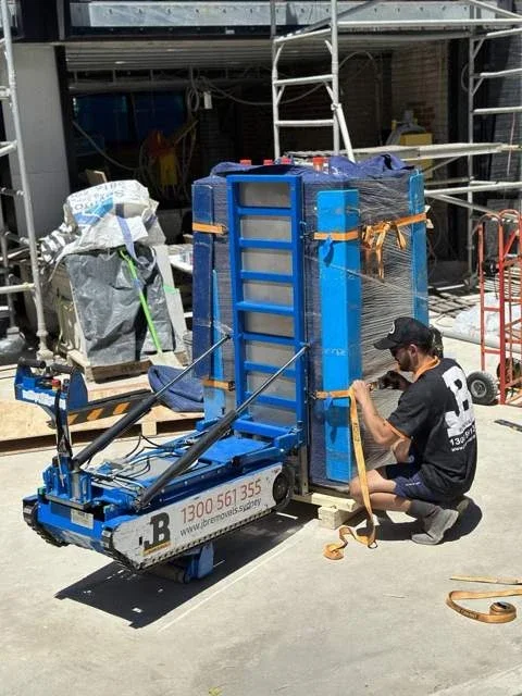 JB removalist securing a protected heating power unit beside a blue tracked stair climber