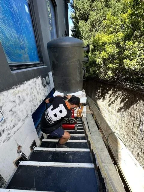 JB removalist controlling a cylindrical heating vessel on a red stair climber along narrow external stairs