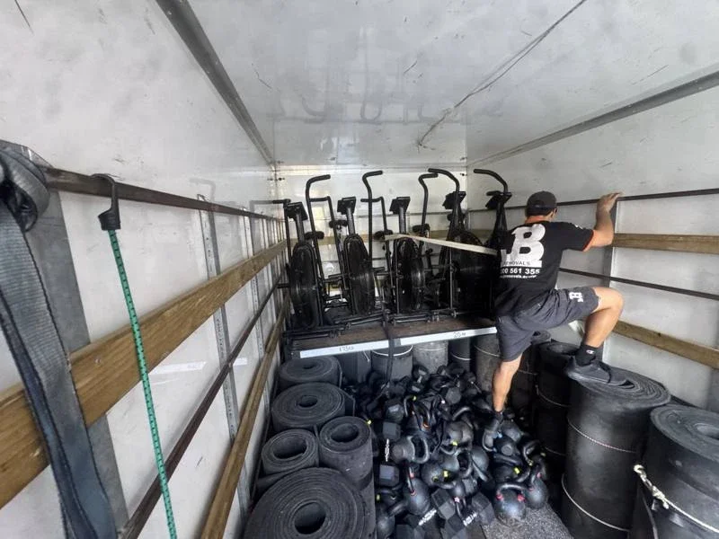 JB Removals truck carrying air bikes, dumbbells, kettlebells and rolled gym flooring