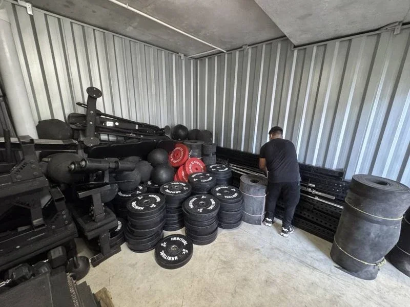 Gym benches, weight plates, frame components and rolled flooring inside the storage unit