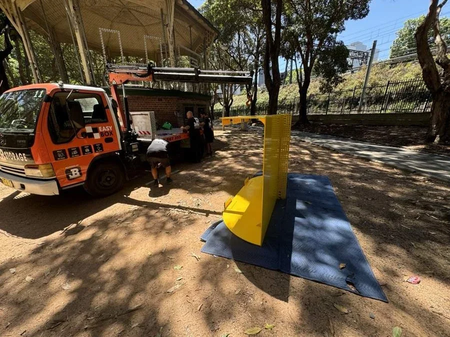 Yellow metal table-tennis table standing on its side over protective blankets beside the crane truck