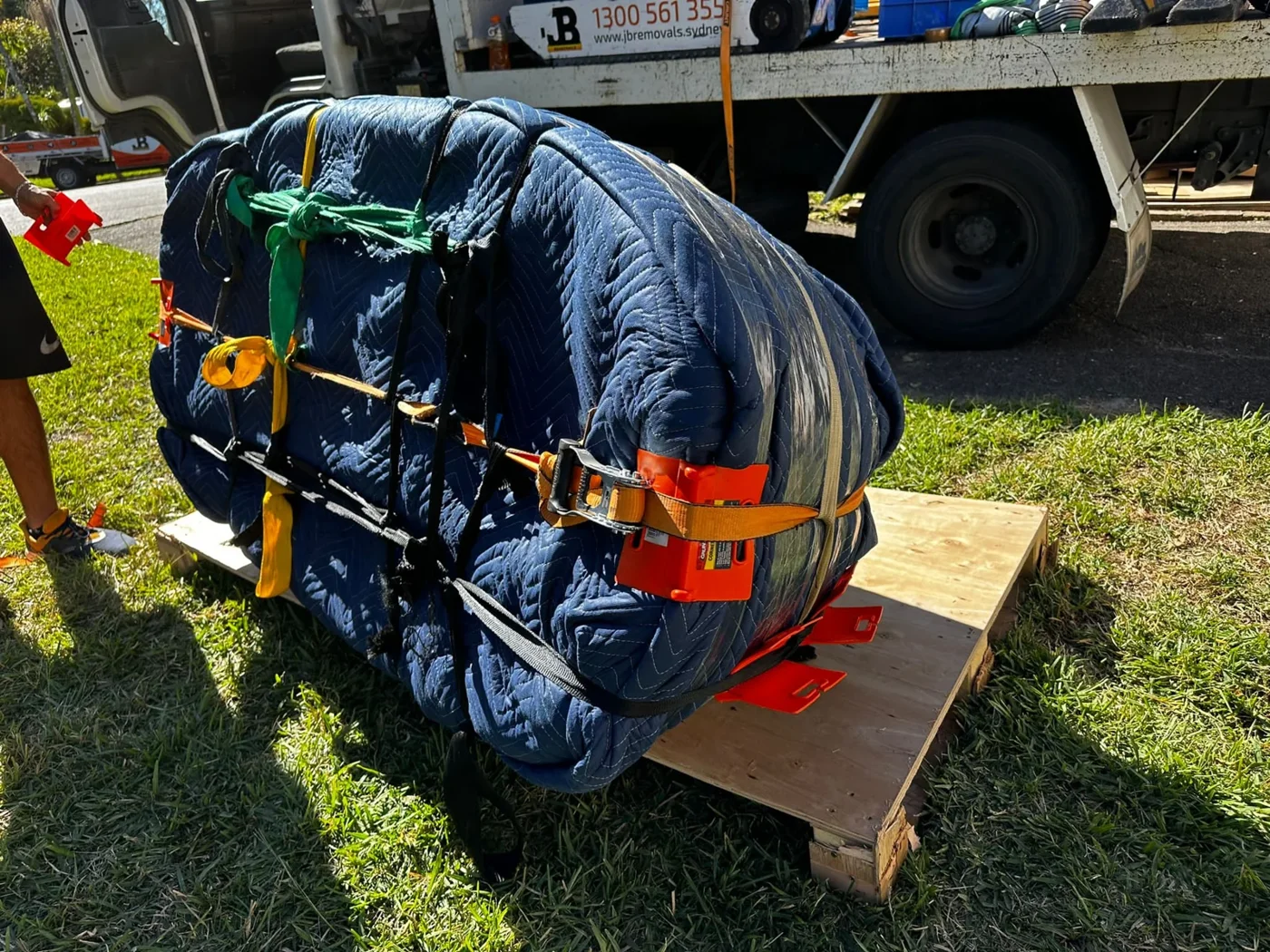 Padded bath with orange handling fixtures and securing straps beside a JB truck