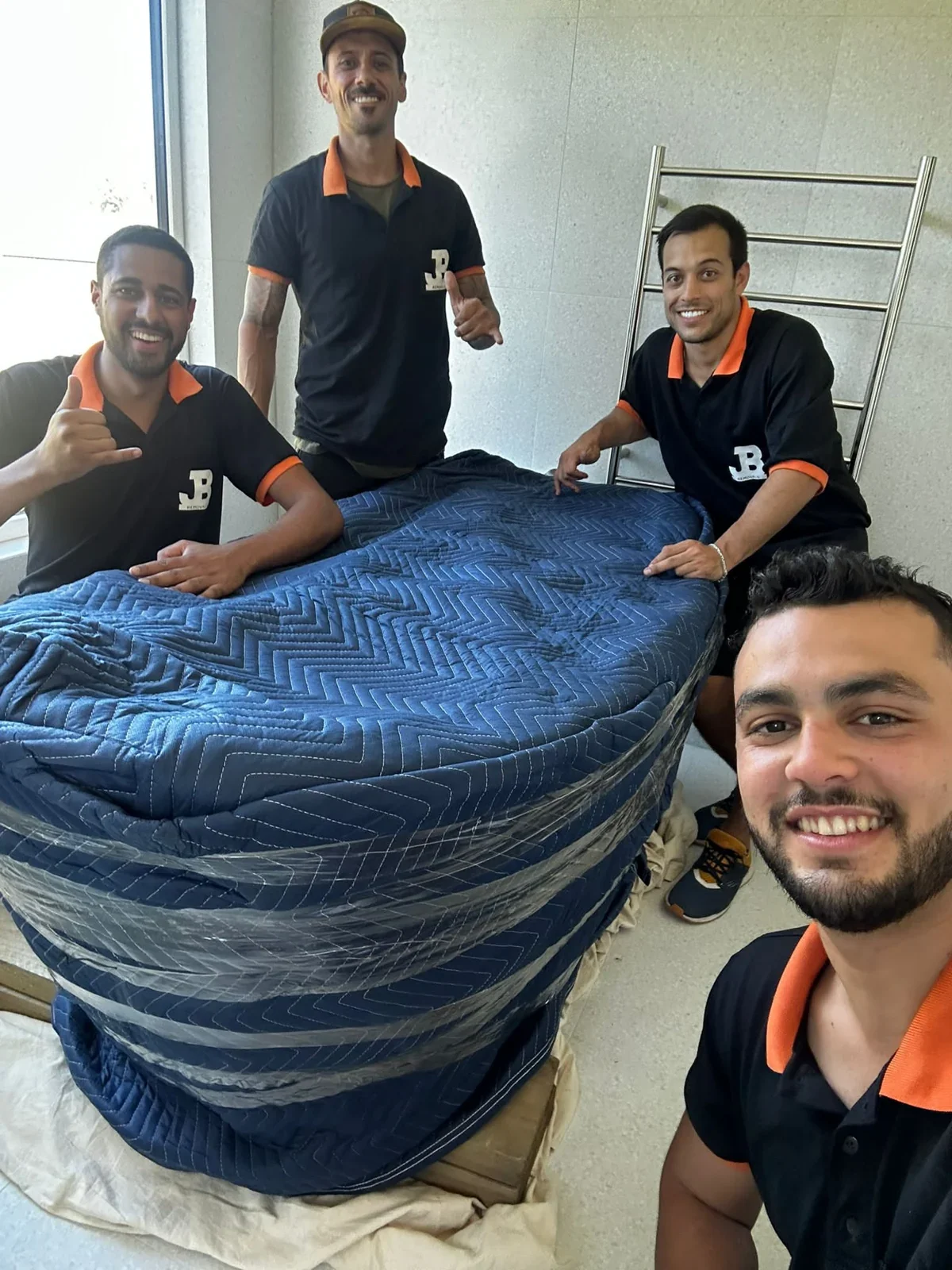 JB team members beside a blanket-wrapped freestanding bath inside the property