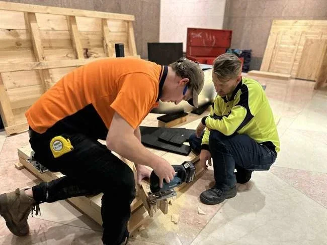 Specialist working on timber crate framing beside padded sculpture pieces