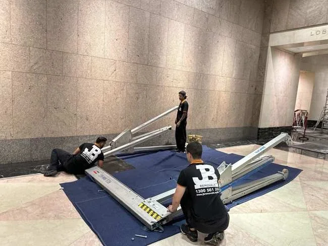 JB team preparing gantry components on protective blankets in the marble lobby