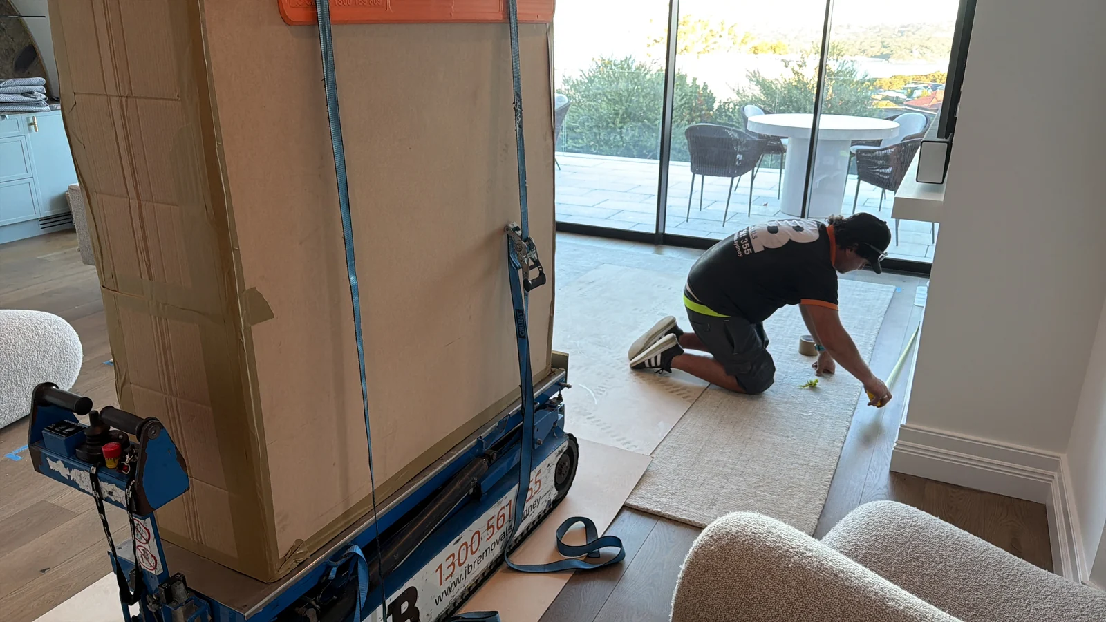 The protected table upright on moving equipment while JB prepares the floor covering.