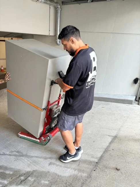 Team member beside the smaller safe secured to a trolley inside a garage
