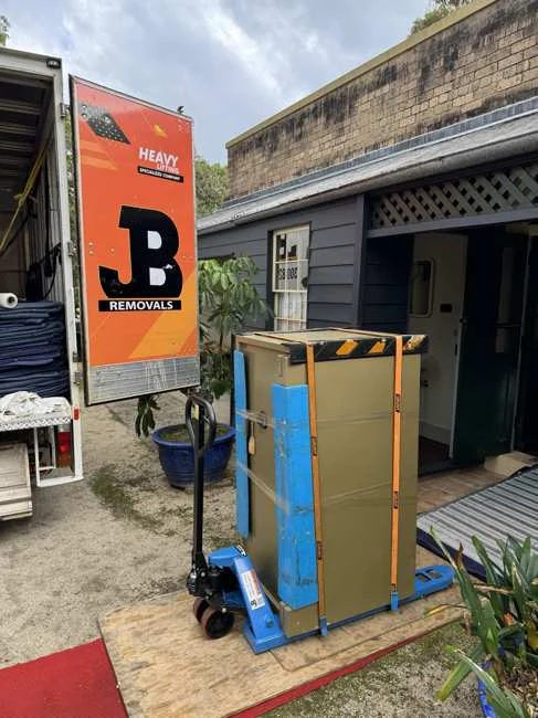 Large protected safe secured on blue specialist safe-moving equipment outside a garage