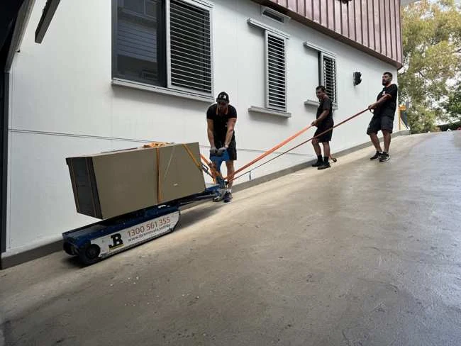 JB team moving a large safe on specialist equipment along a steep residential driveway