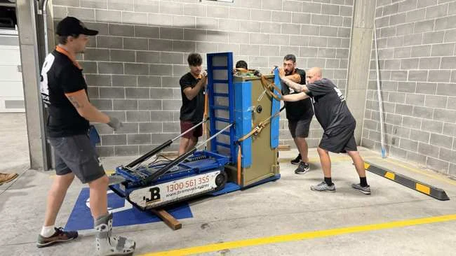 JB team handling a large protected safe on specialist equipment in a garage