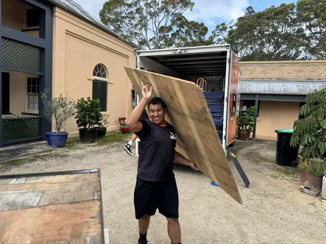 JB team member carrying a timber board beside the removal truck