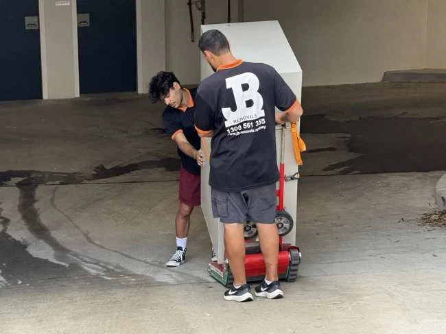 JB team positioning a smaller safe on a red wheeled trolley