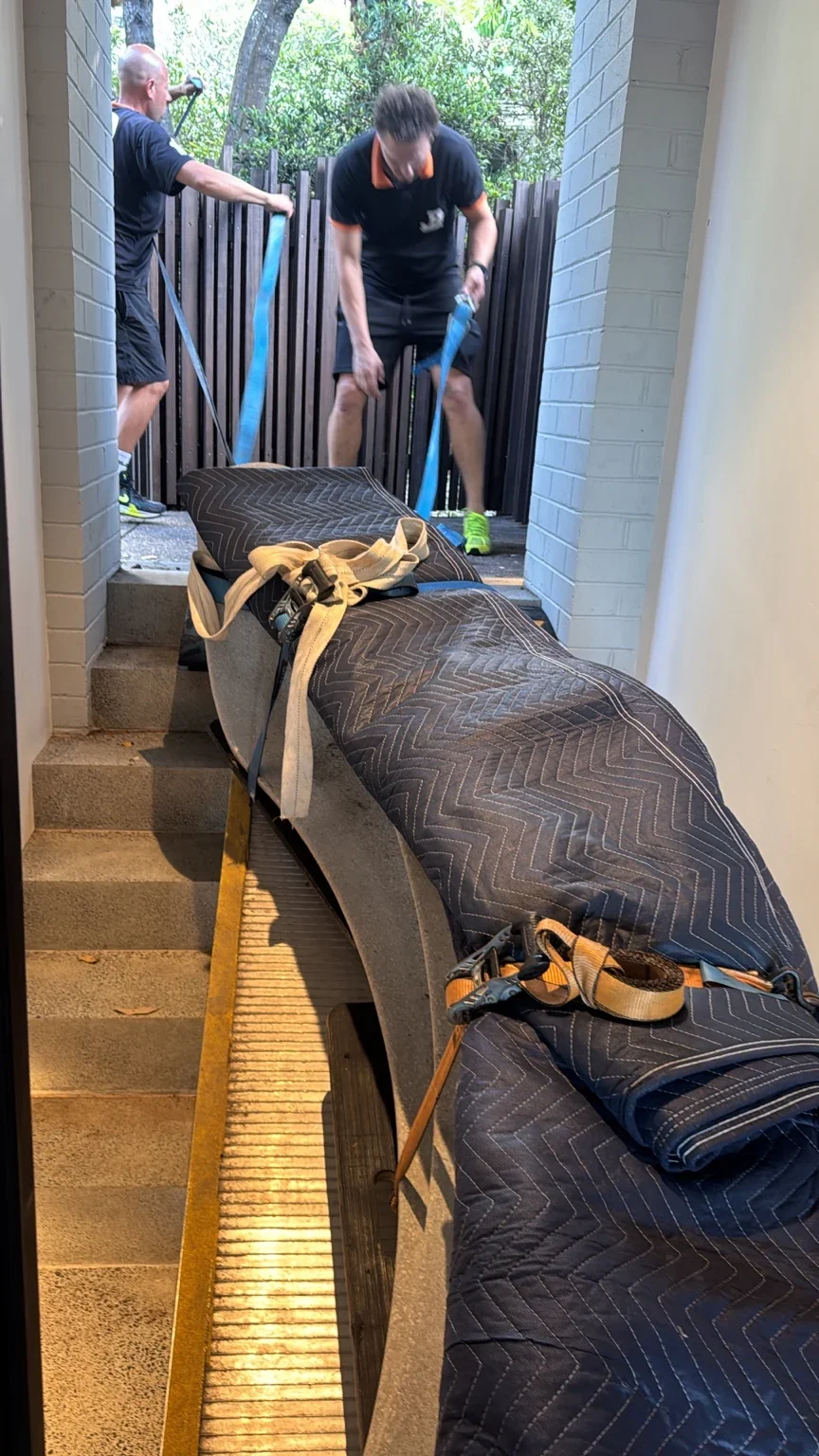 JB crew handling a blanket-wrapped marble bench beside the narrow stair ramp