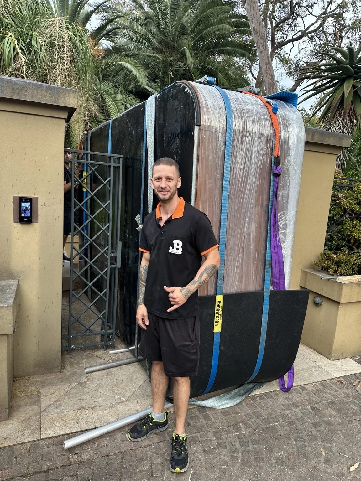 JB removalist beside the wrapped spa held on its side near an outdoor gate