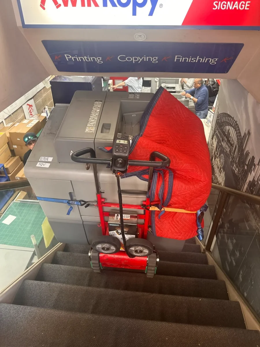 Commercial printer on a red stair climber on the staircase with a protective blanket and straps