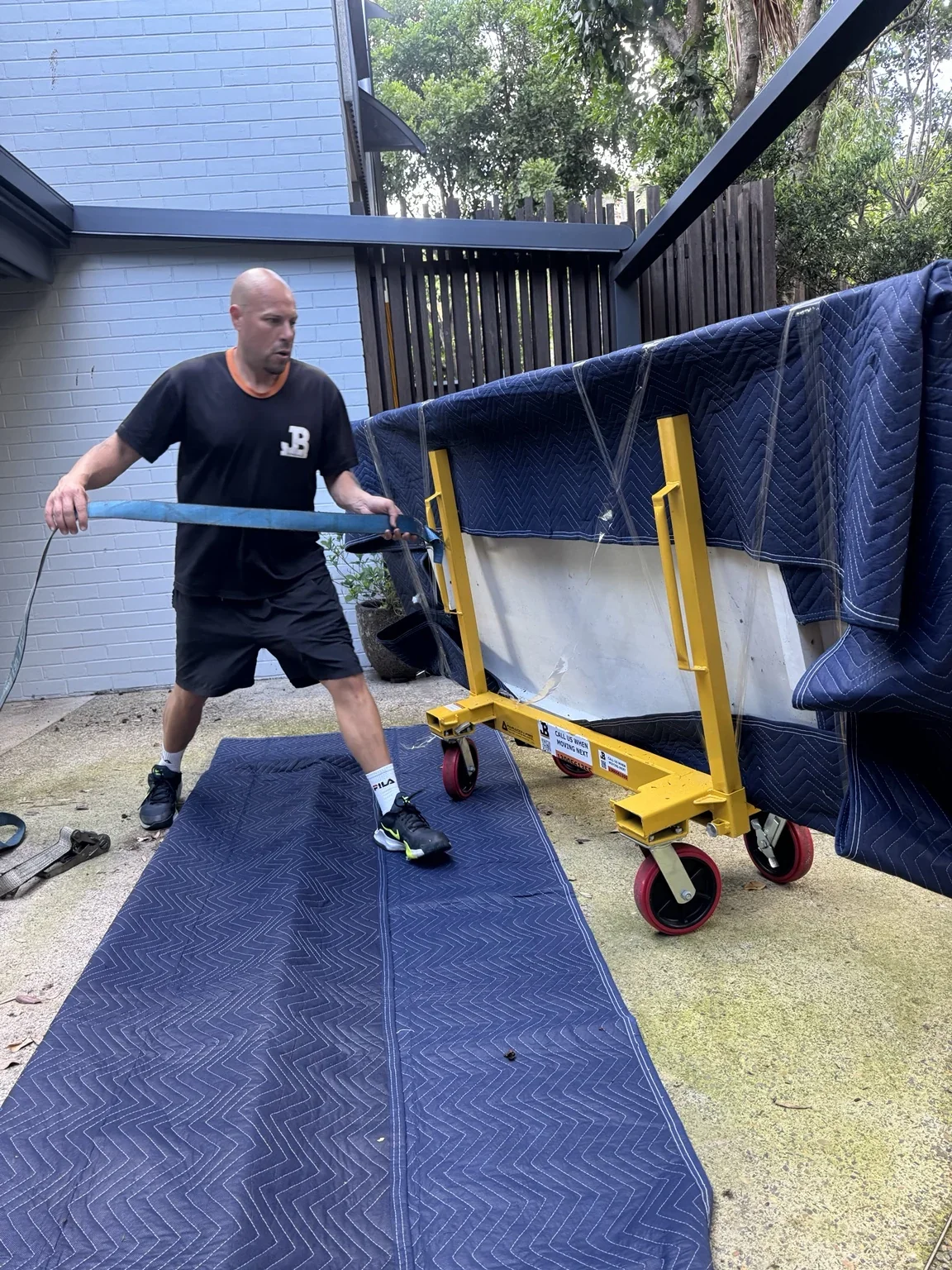 JB removalist beside a wrapped marble bench on a yellow wheeled frame