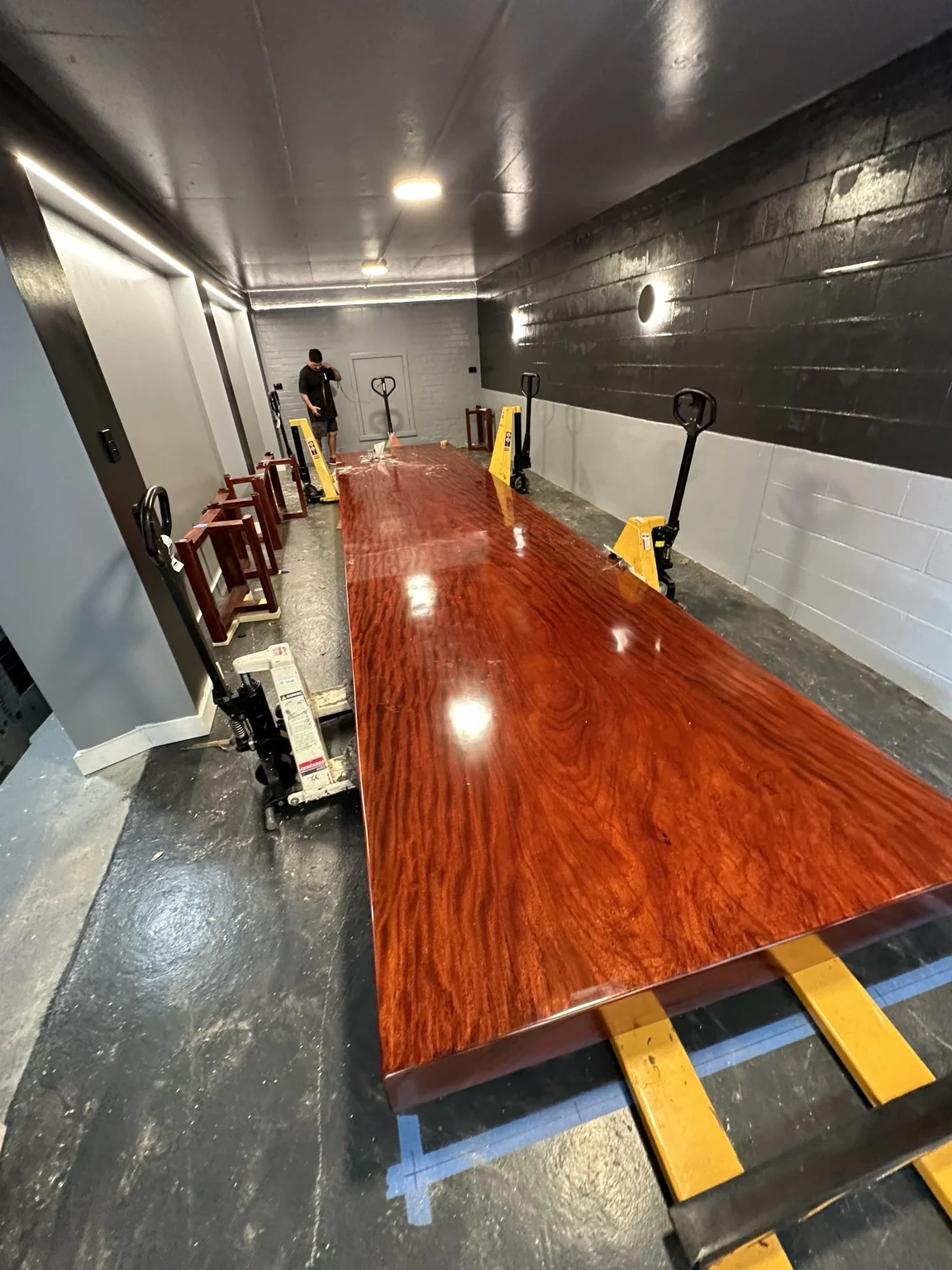 Polished long timber tabletop with lifting equipment positioned along its length