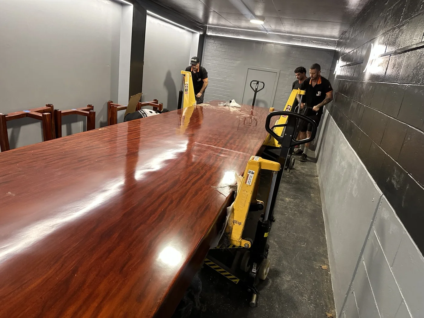 JB Removals crew operating lifting equipment beside the polished oversized tabletop