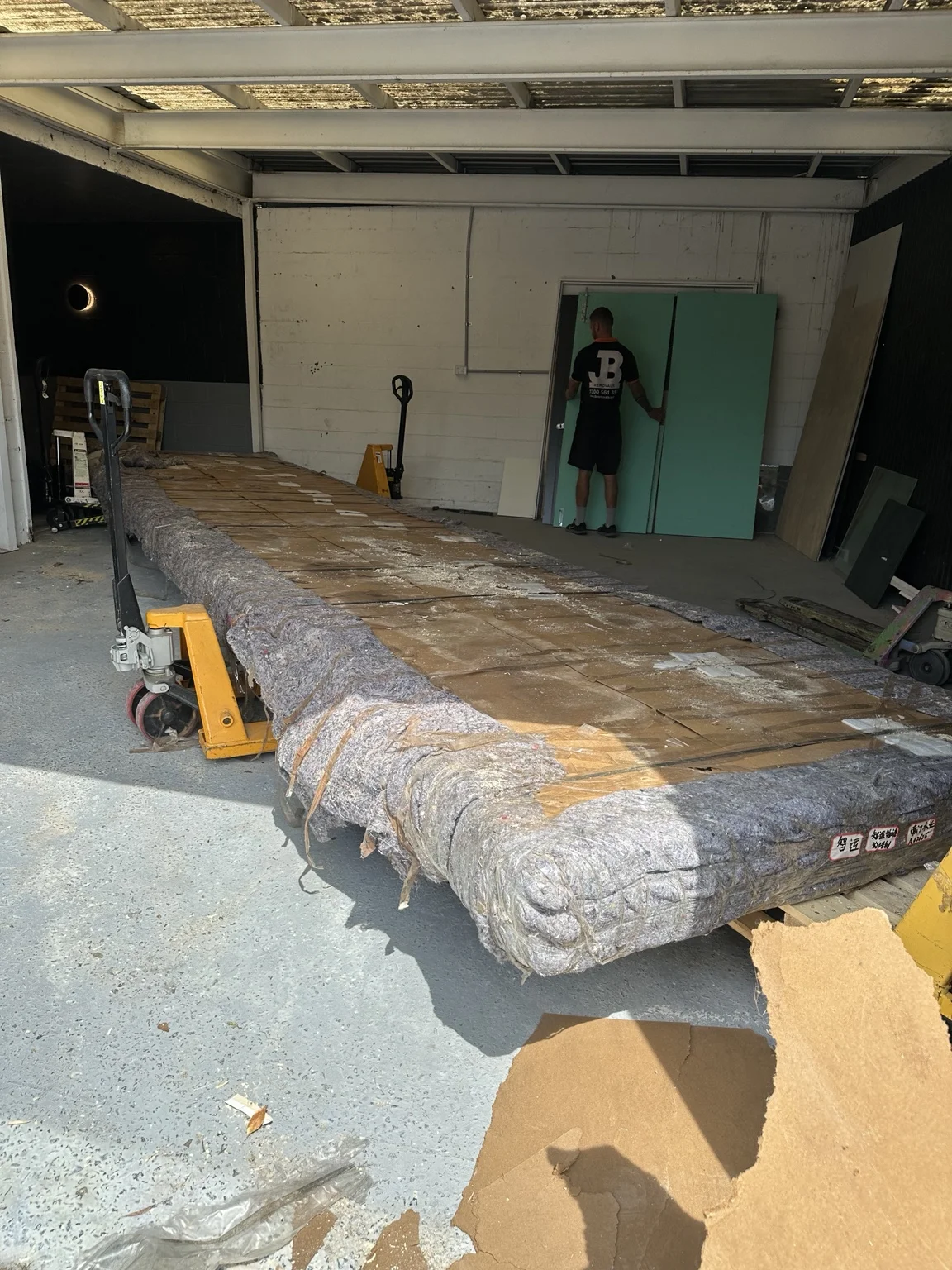 Long tabletop wrapped in blankets and cardboard with lifting equipment positioned alongside